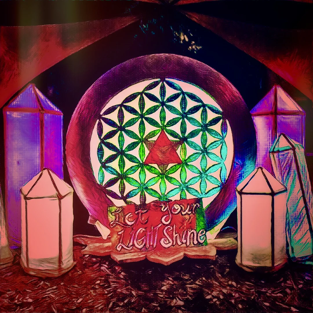 An illuminated art piece featuring glowing crystal pillars around a circular Flower of Life design with a sign that reads Let Your Light Shine.
