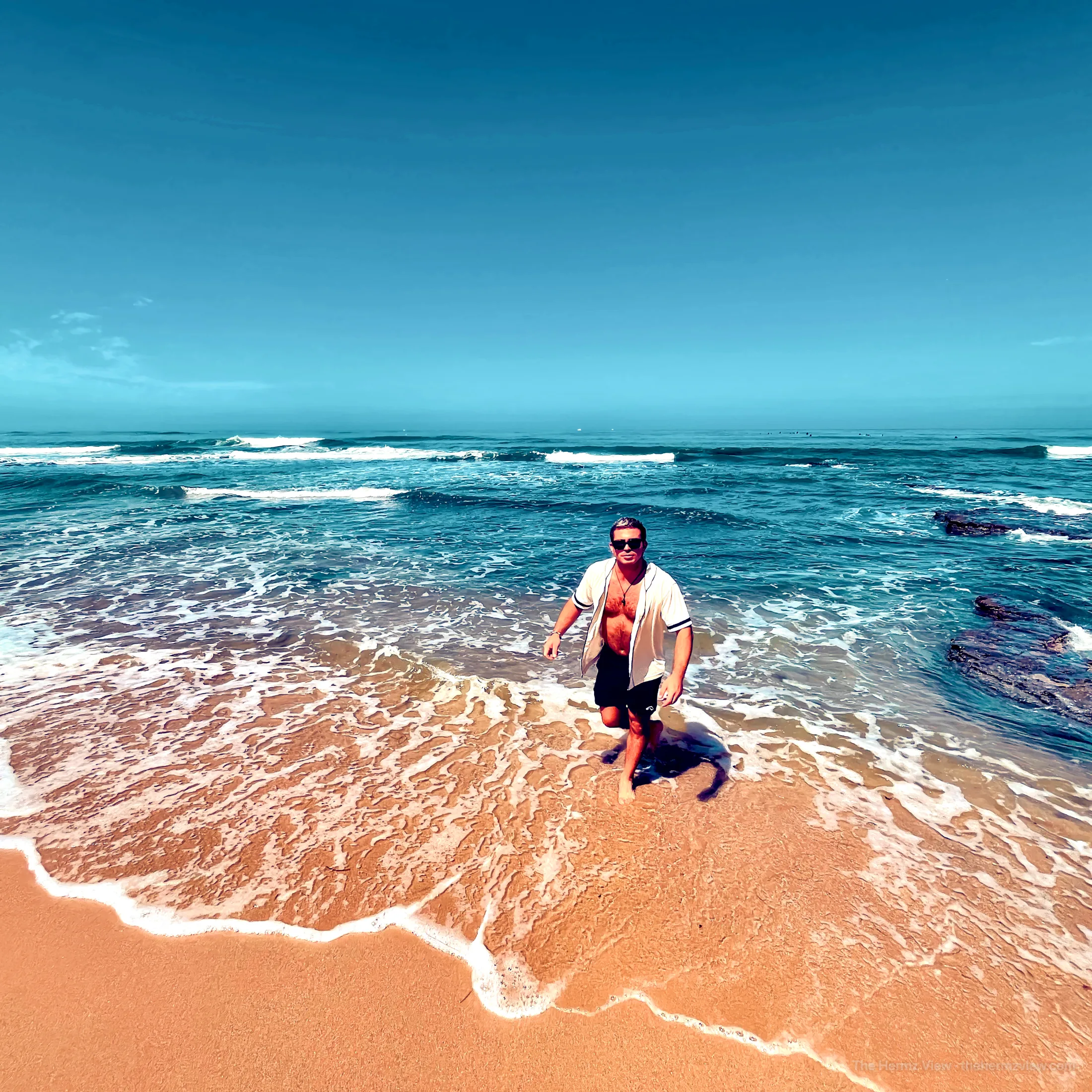 Walking through shallow ocean foam onto a sandy shore.