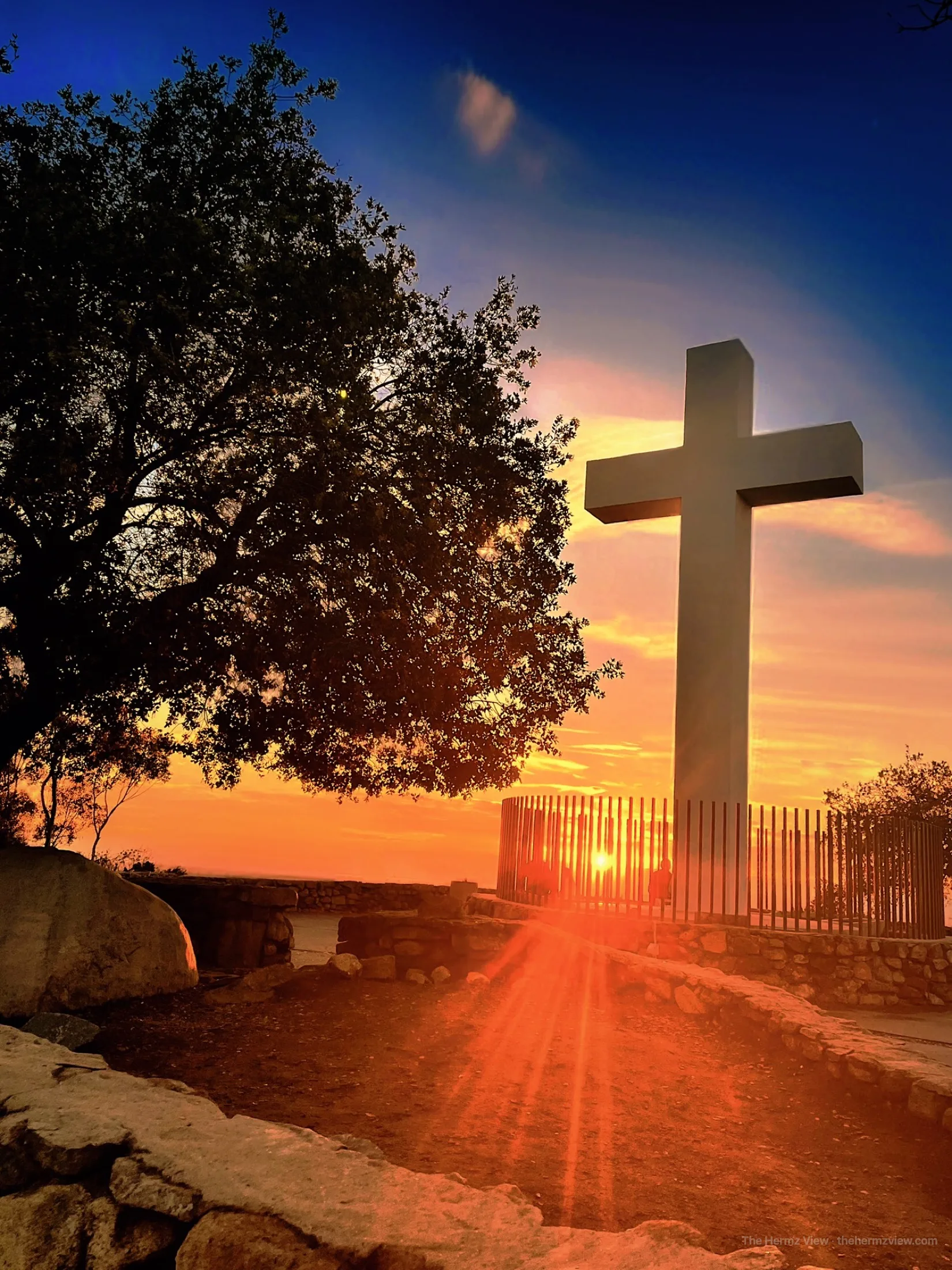 A hillside cross silhouetted against sunset