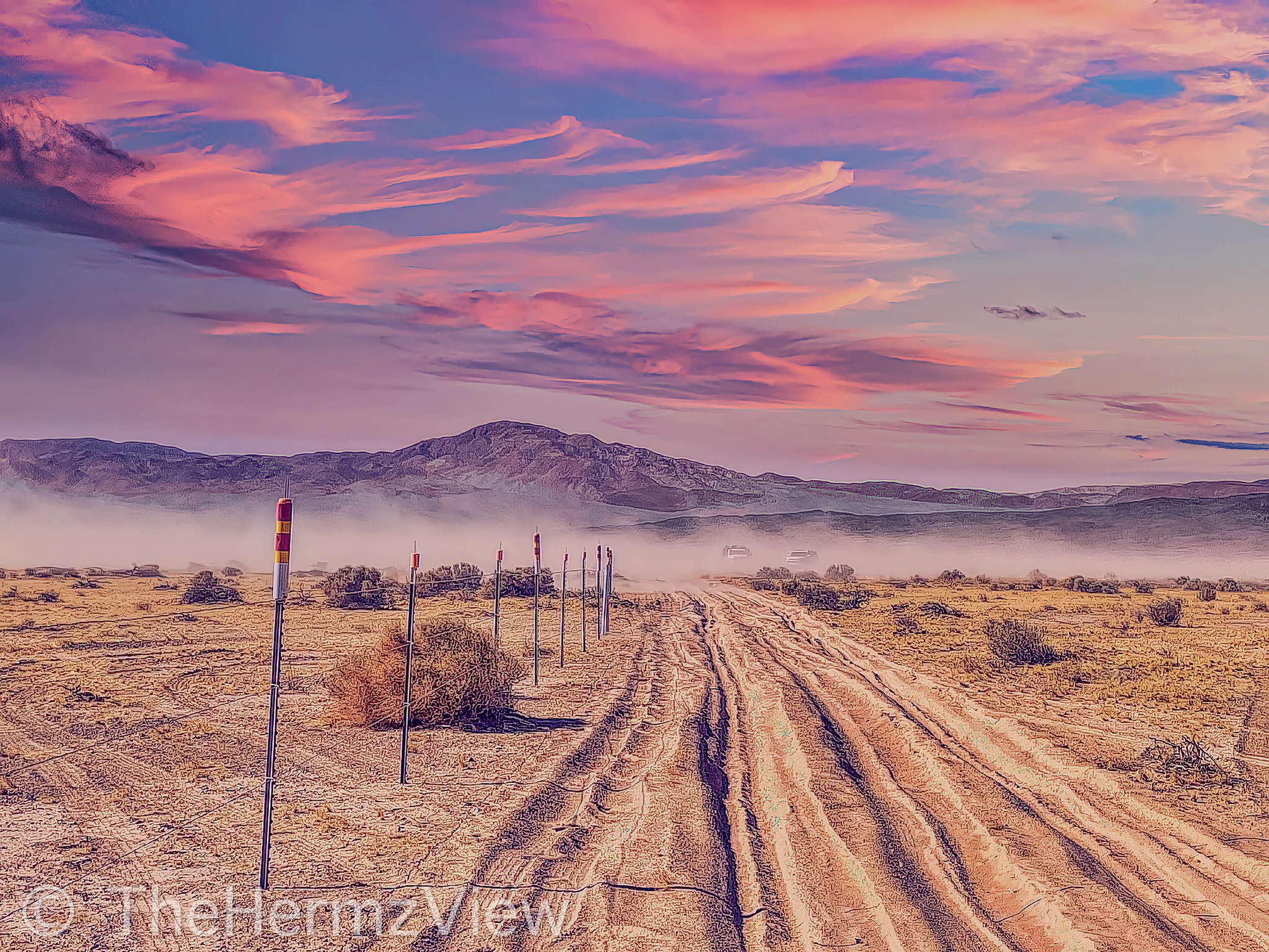 A heavily rutted dirt road in an arid desert landscape stretches toward distant mountains under a vivid pink and purple sunset sky.